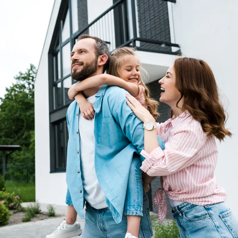 BarmeniaGothaer Wohngebäudeversicherung: Eine Familie steht vor einem Haus und lacht BarmeniaGothaer Wohngebäudeversicherung: Eine Familie steht vor einem Haus und lacht