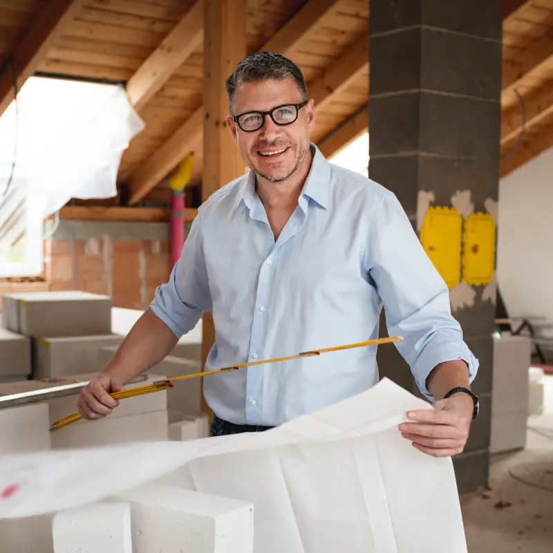 BarmeniaGothaer Bauherrenhaftpflicht: Ein Mann hat einen Bauplan in der Hand und steht auf einer Baustelle BarmeniaGothaer Bauherrenhaftpflicht: Ein Mann hat einen Bauplan in der Hand und steht auf einer Baustelle
