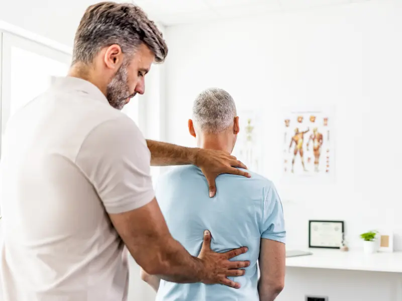Ein Arzt untersucht einen Patienten aufgrund eines Bandscheibenvorfalls Ein Arzt untersucht einen Patienten aufgrund eines Bandscheibenvorfalls