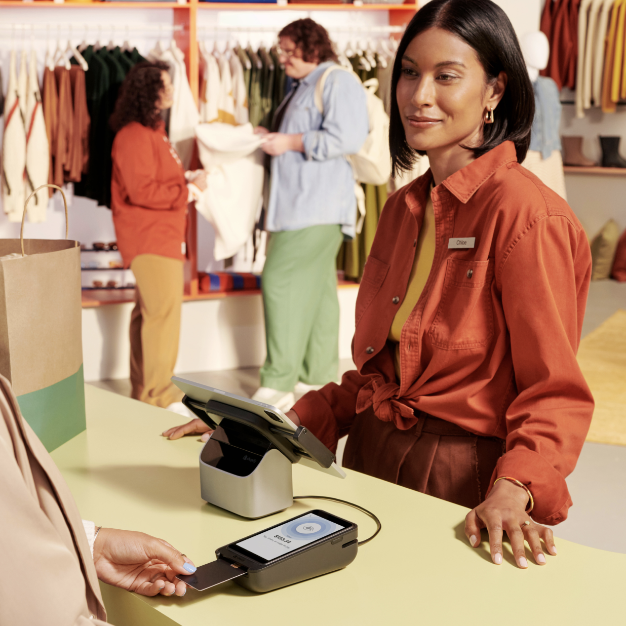 عميلة تقف عند طاولة الدفع في متجر مزدحم وتدفع ثمن مشترياتها باستخدام Shopify POS.