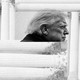 A black-and-white image of President Trump's side profile surrounded by stacks of Supreme Court building columns