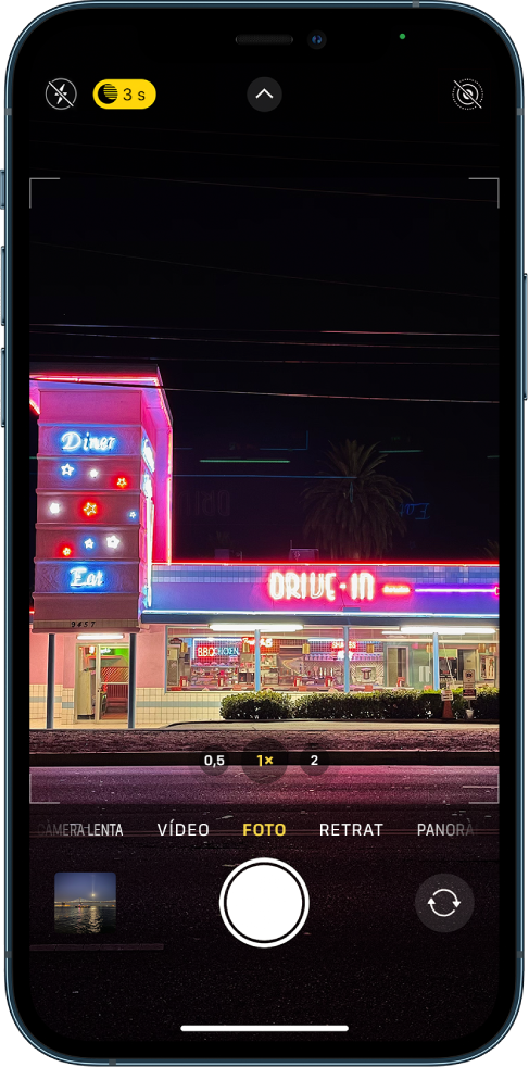Pantalla de l’app Càmera en el mode Foto. Els botons de flaix i mode Nit són a l’angle superior esquerre de la pantalla. El flaix està desactivat i el mode Nit està activat. El botó dels controls de la càmera són al centre de la part superior, i el botó Live Photo a l’angle superior dret. A la part inferior de la pantalla, d’esquerra a dreta, hi ha el botó visor de fotos i vídeos, el botó per fer una foto i el botó selector de la càmera posterior.