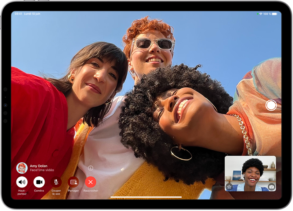 Un appel FaceTime en groupe avec quatre participants. Les commandes FaceTime figurent en bas à gauche de l’écran, avec notamment les boutons Haut-parleur, Appareil photo, « Couper le son », Partager et Fin. L’image de l’appelant s’affiche dans un petit rectangle en bas à droite.