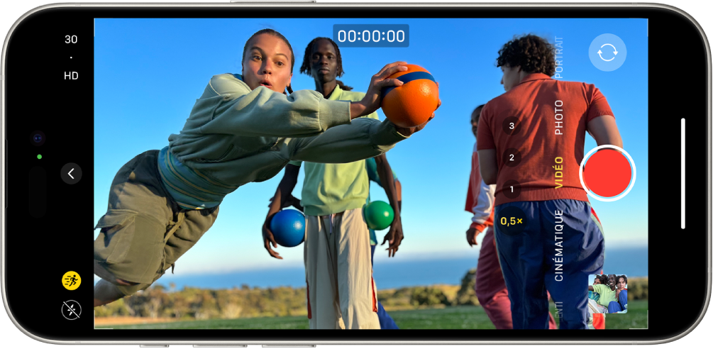 L’iPhone est en position horizontale. Appareil photo est ouvert et en mode Vidéo. Une personne fait du jogging dans le cadre de l’appareil photo. Le bouton Flash se trouve dans le coin inférieur gauche de l’écran. Le bouton « Commandes de l’appareil photo » se situe au centre à gauche de l’écran. Dans le coin supérieur gauche se trouvent des interrupteurs pour changer la résolution de la vidéo et sa fréquence d’images. Le bouton Action est activé dans le coin supérieur gauche. Sur le côté droit, de haut en bas, se trouvent le bouton « Sélecteur de caméra - face arrière », le bouton Enregistrer et le bouton « Visualiseur de photos et vidéos ». Dans le viseur, une personne court.