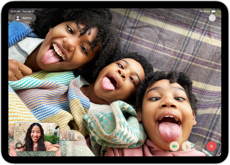 एक FaceTime वीडियो कॉल प्रगति में है, जिसमें सबसे नीचे बाईं ओर एक प्रतिभागी दिखाई दे रहा है। स्क्रीन के बाकी हिस्से में तीन अन्य प्रतिभागियों की एक इमेज दिखाई दे रही है। नीचे दाईं ओर कैमरा, माइक्रोफ़ोन, अधिक और “कॉल बंद करें” बटन हैं।