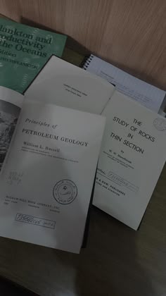 several papers are stacked on top of each other in front of a wooden table with a pen and pencil