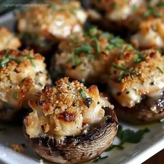 some stuffed mushrooms are sitting on a white plate and garnished with parmesan cheese