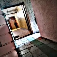 an open door leading into a room with tile flooring and walls that have peeling paint on them