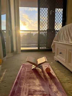 an open book sitting on top of a rug next to a bed in a bedroom