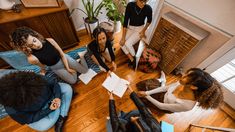 a group of people sitting on top of a wooden floor next to each other in a living room