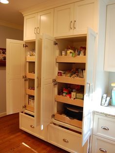 an open pantry door in a kitchen with wooden floors and white cabinets on both sides