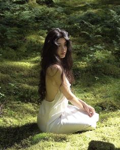 a woman sitting in the grass with her hands on her knees