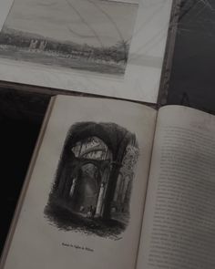 an open book sitting on top of a table next to pictures and drawings in black and white