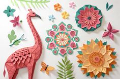some paper flowers and an origami giraffe are arranged on a white surface