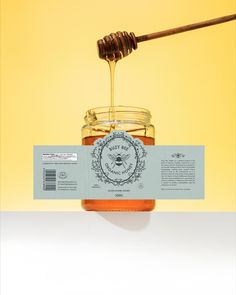 a jar of honey with a wooden stick sticking out of it's top, on a yellow background