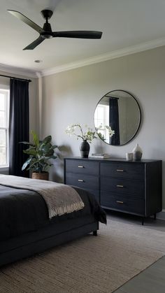 a bedroom with a bed, dresser and ceiling fan in front of a large window