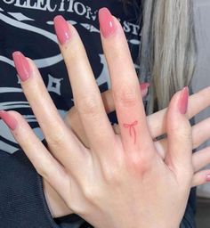 a woman's hand with a red bow tattoo on her left thumb and finger