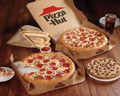 three pizzas in boxes with different toppings on the table next to each other