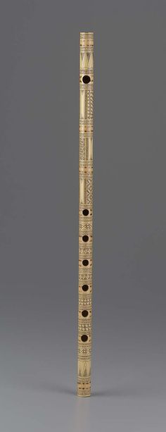 a tall wooden object with intricate designs on it's face and sides, standing in front of a gray background