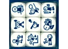 six white dices with blue designs on them in a plastic box, one has an image of people and animals