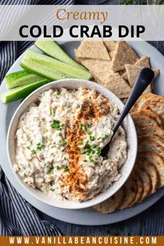 a white plate with crackers, celery and chips on it that says creamy cold crab dip