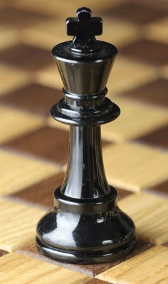 a black and silver chess piece sitting on top of a wooden table