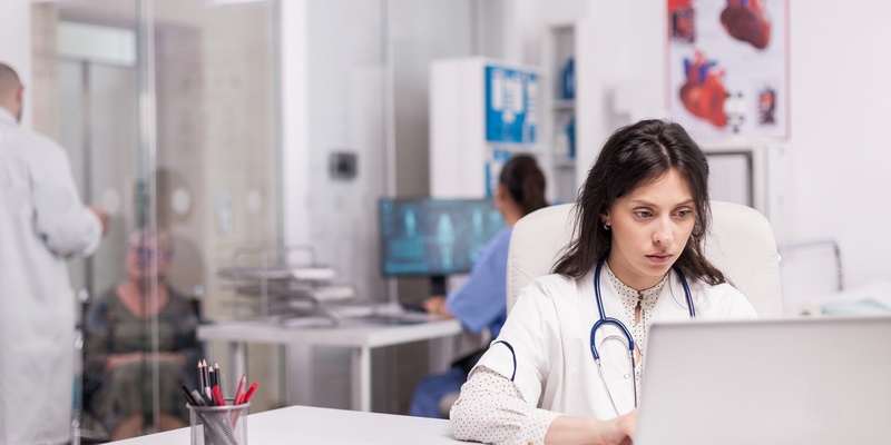 Woman sitting in front of a laptop typing.