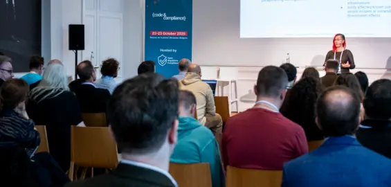 A room full of people listening to a public speaker.