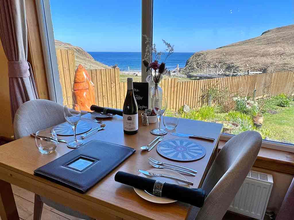 HOME 4 A dinig table set fo two infront of a window looking out over the Atlantic