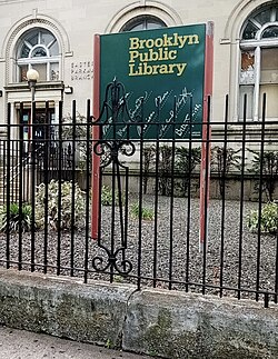 Green sign with "Brooklyn Public Library" text in yellow.