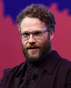 Seth Rogen, a white man with glasses, a beard, and a purple suit