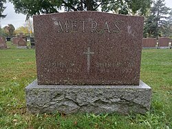 Red granite upright stone inscribed with names, birth and death dates of Metras and his wife