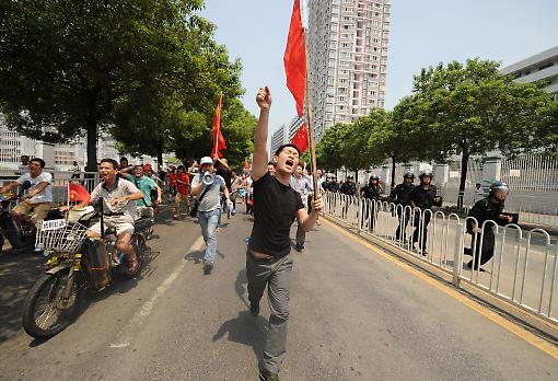 An anti-Japan protester runs down the street followed by riot police during a protest last year. An anti-Japan protester runs down the street followed by riot police