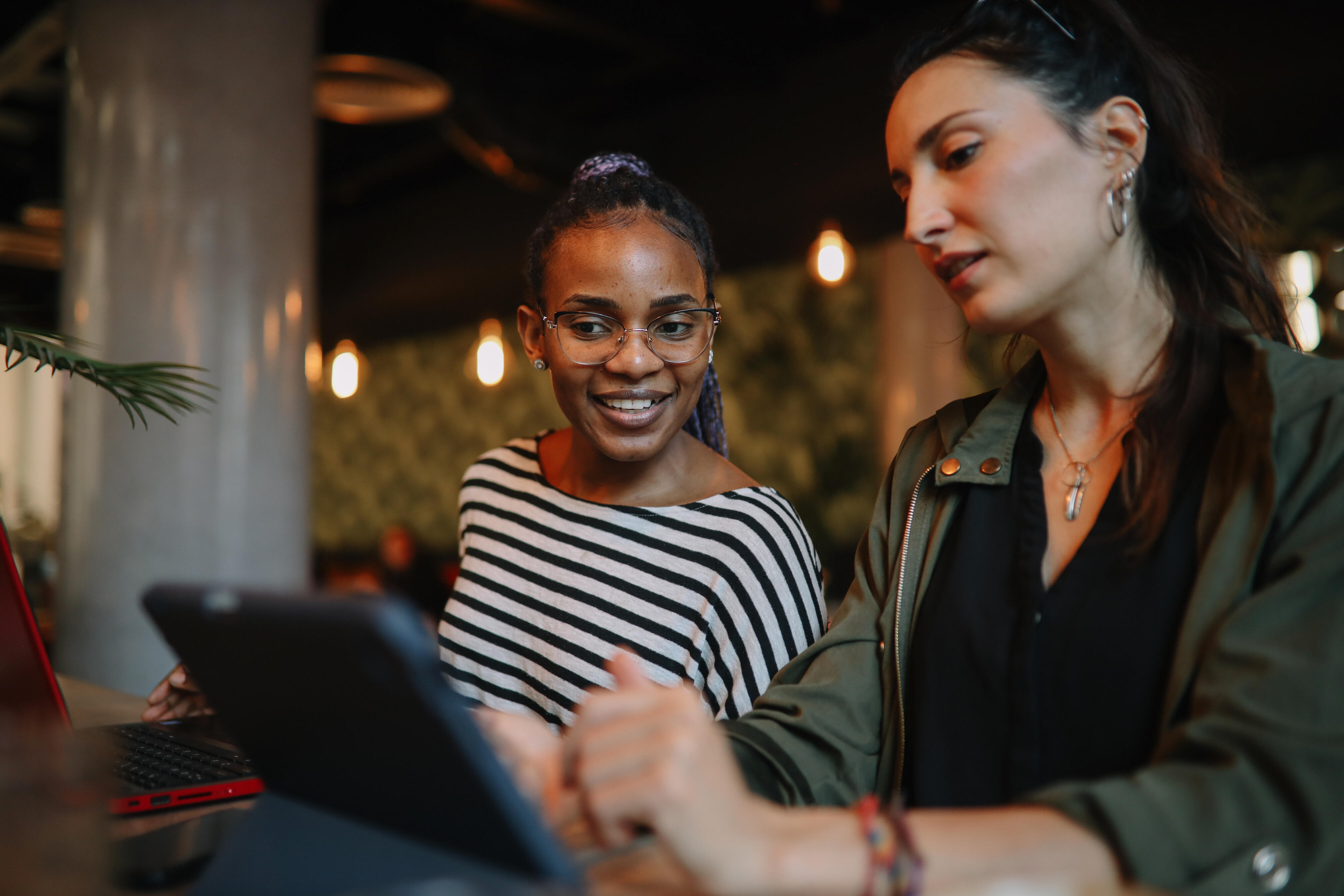 Two women looking at tablet in restaurant
